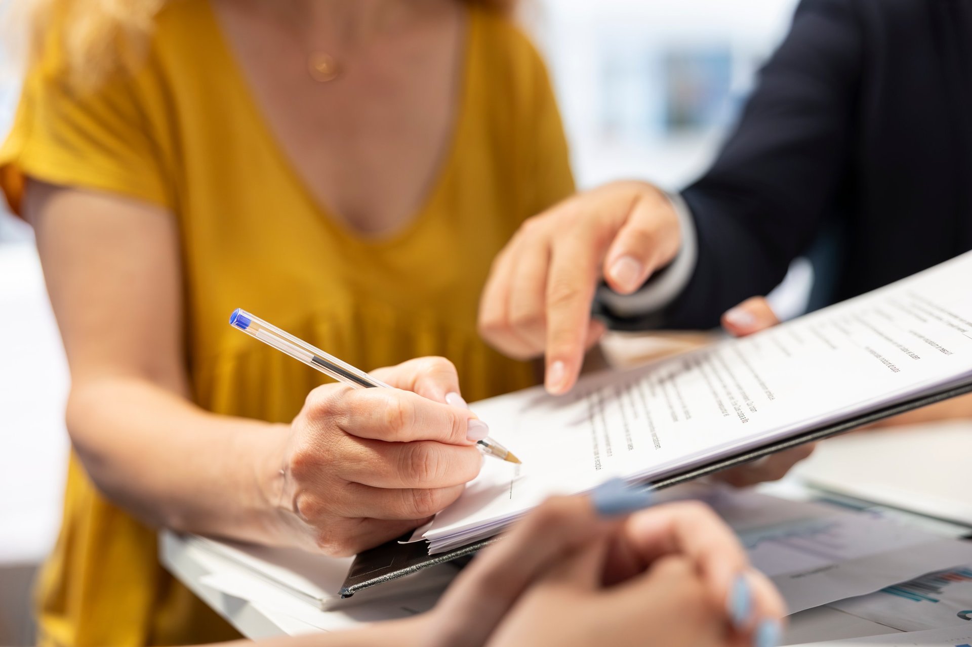 Person signing document with pen