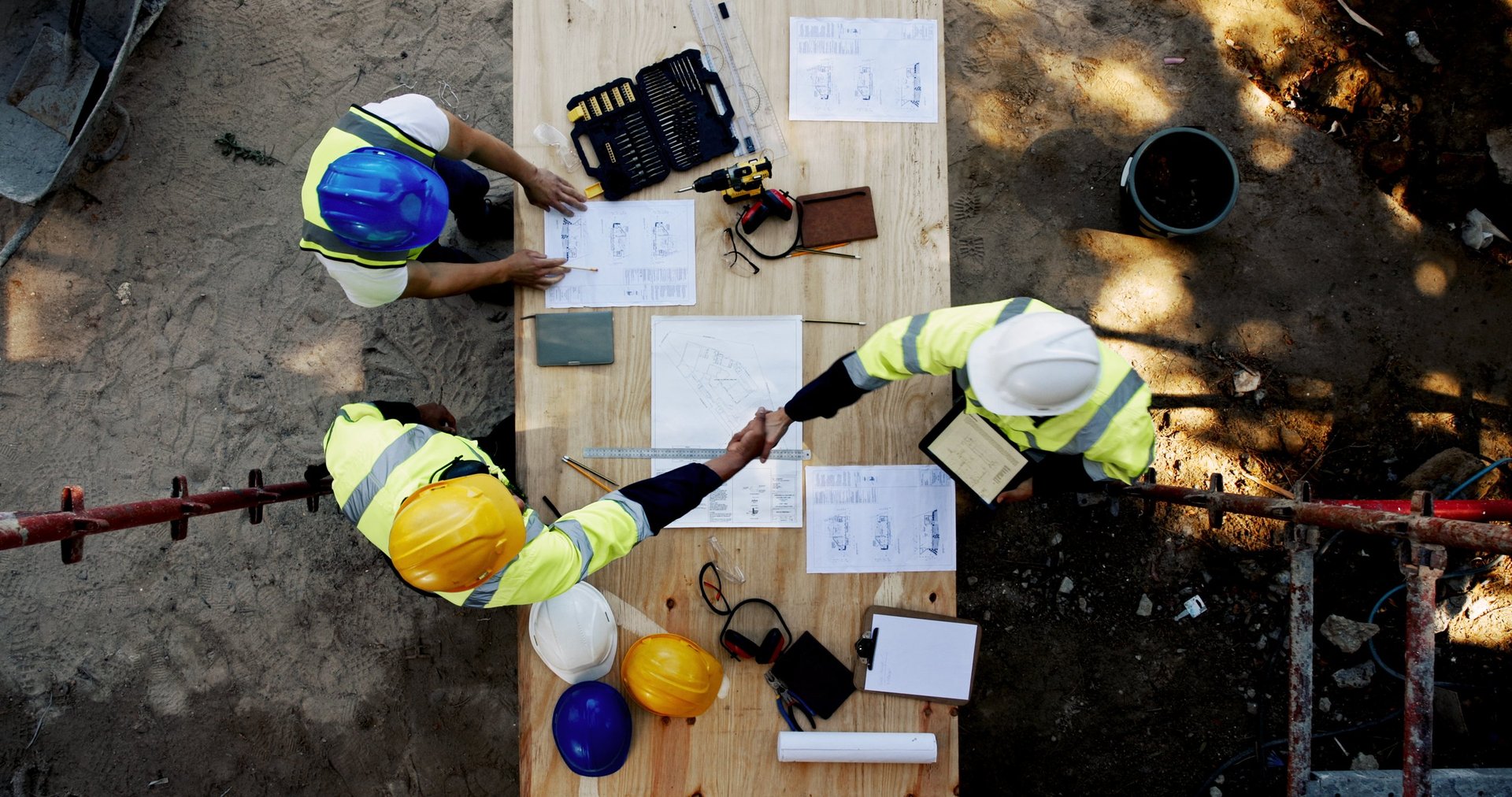 Blueprint, architecture and men at table shaking hands for collaboration, agreement and inspection