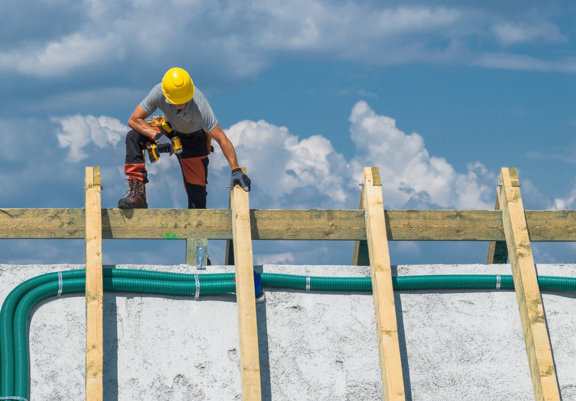 Worker carefully places wooden beams on a roof structure while standing on scaffolding