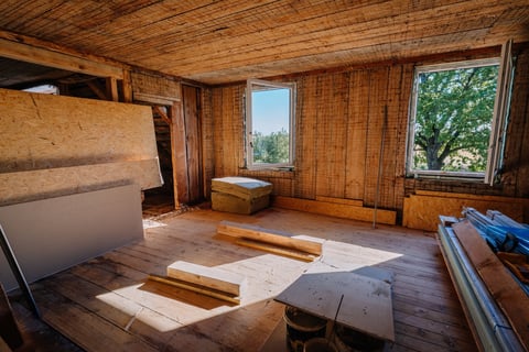 Room under renovation with wood panel walls and natural light